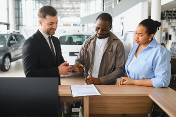 Car salesman helping couple choosing new vehicle in dealership