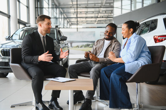 Car salesman explaining offer to african american couple in dealership