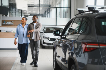 Couple choosing new car in dealership showroom