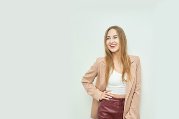 Obraz premium Smiling young caucasian female in beige blazer and red skirt against light background.