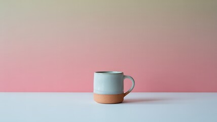 A simple ceramic mug with a terracotta base sits on a white surface against a soft pink and yellow gradient background