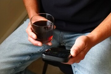 Man holding phone and glass of drink