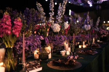 Dramatic Nighttime Floral Centerpiece with Purple and Pink Blooms, Candles, and Emerald Green Table Decor