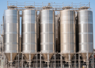 Industrial storage silos for grain or liquid materials at a manufacturing facility under clear blue sky