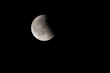Moon partially covered during a lunar eclipse viewed from a dark location at night