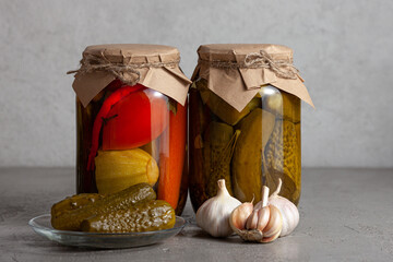 Two glass jars filled with assorted pickled vegetables, sealed with kraft paper and twine.