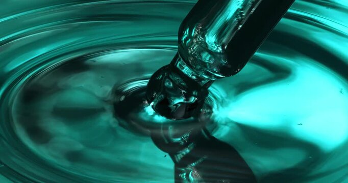 Slow Motion Macro of Blue liquid oil drop hitting surface and creating circular waves, elegant macro abstract shot in deep turquoise tones at 1000 fps