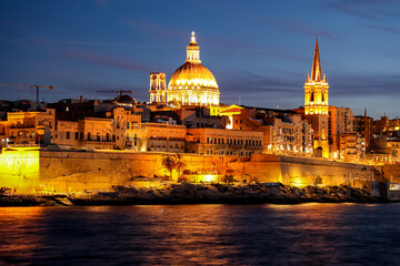 Evening view of Valletta, Malta, showcasing the warmly lit Basilica of Our Lady of Mount Carmel...