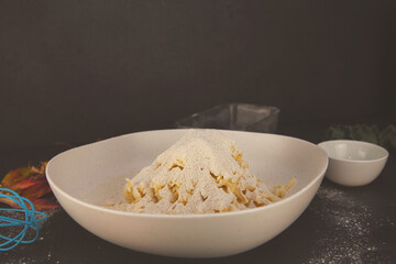 Grated butter mixed into flour with eggs, oil and autumn leaves around — cozy homemade baking preparation in a rustic fall kitchen.