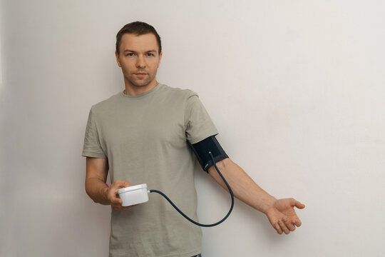 Man measuring blood pressure with digital monitor at home (wide)