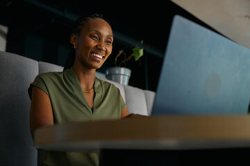 Smiling young black businesswoman using laptop at desk in office