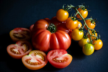 Assortment of fresh heirloom tomatoes and cherry tomatoes on black background
