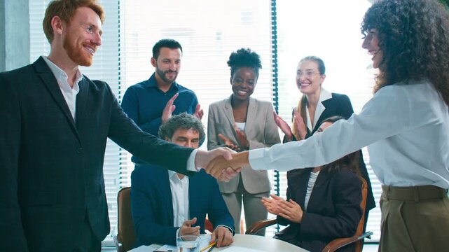 Smiling businesspeople shaking hands after signing contract. Team clapping and celebrating agreement in office. Successful partnership and cooperation between colleagues during meeting.