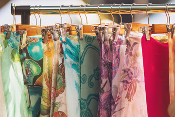 Colorful scarves hang elegantly in the sunlight at a vibrant outdoor market during a lively...