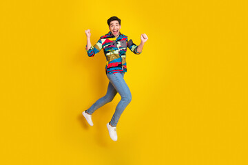 Energetic young man jumps in a colorful shirt against a bright yellow background conveying fun fashion and lively lifestyle for advertising and marketing
