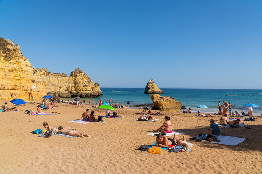Camilo Beach (Praia do Camilo) people were sunbathing on the beach and swimming in the ocean. Ponta da Piedade near Lagos in Algarve, Portugal. - Powered by Adobe