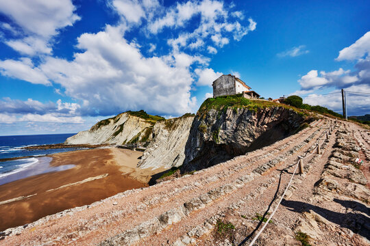 The Flysch cliffs and coastline with the San Telmo Hermitage (Ermita de San Telmo) in the background, built in 1626, a small chapel located in Zumaia, in the Basque Country of Spain, Europe 
