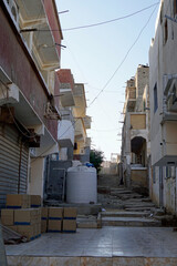 Narrow, dirty dirt road between crumbling multi-story buildings