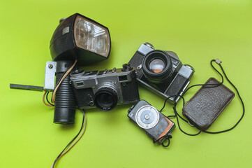 A set of rare photographic equipment. Camera, flash, film and exposure meter on a green background....