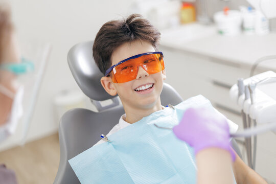 Medicine pediatric dentistry healthcare. Smiling caucasian young male at dental clinic wearing protective eyewear. - Powered by Adobe
