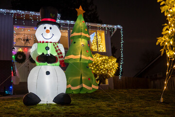 Luminous inflatable figure of Snowman and Christmas tree decorating front yard at night
