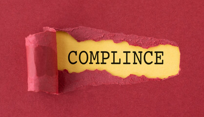 A torn piece of paper with the word Compliance written in black on a red background