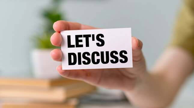 A person is holding a white card that says "Let's discuss"