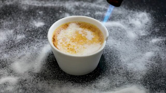 Cr&egrave;me br&ucirc;l&eacute;e, creme brul&eacute;. Classic creme brul&eacute;e being flamb&eacute;ed. Burning, flames, cabbage, vanilla bean, blowtorch, sugar, blowtorch.