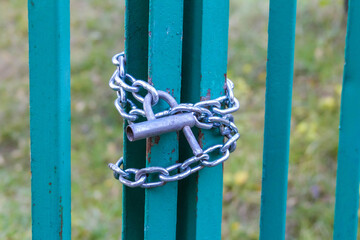 Decorative turquoise metal butterfly sculpture mounted on striped fence pole in Warsaw urban park setting. High quality photograph.