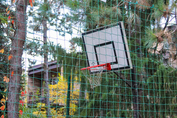 Basketball hoop and backboard mounted on wire fence in autumn Warsaw neighborhood outdoor sports court. High quality photograph.