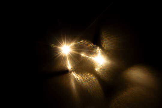 Lens Flare. Light over black background. Easy to add overlay or screen filter over photos. Abstract sun burst with digital lens flare background. Gleams rounded and hexagonal shapes, rainbow halo.
