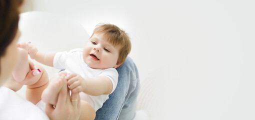 Adorable 7 month old baby laughing while lying on mother's lap, over the shoulder shot. mom and baby