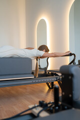 Woman doing Swan exercise on Pilates Reformer for the chest and back muscles, focusing on flexibility, strength, and control with determination