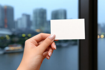 Hand holding blank business card cityscape background blurred buildings natural light closeup professional modern urban opportunity networking confident creative