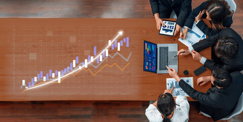 A diverse team of professionals collaborates in a modern office, analyzing data on laptops and charts to strategize for business growth and success. Axiom