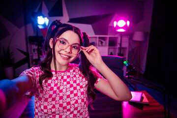 Energetic female streamer enjoying podcasting in a modern neon-lit home studio setup with creative workspace