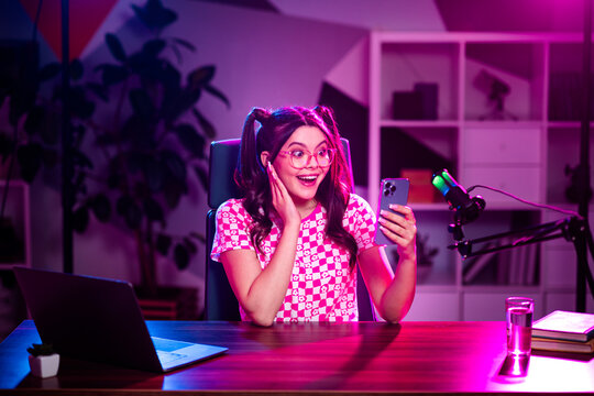 Young female content creator interacting in a neon-lit workspace, emphasizing online interactions, style, and modern media