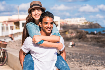 Young mixed-ethnicity couple enjoying time together outdoors during a relaxed day out, walking, laughing and sharing a romantic moment; youthful love, connection, leisure lifestyle and authentic 
