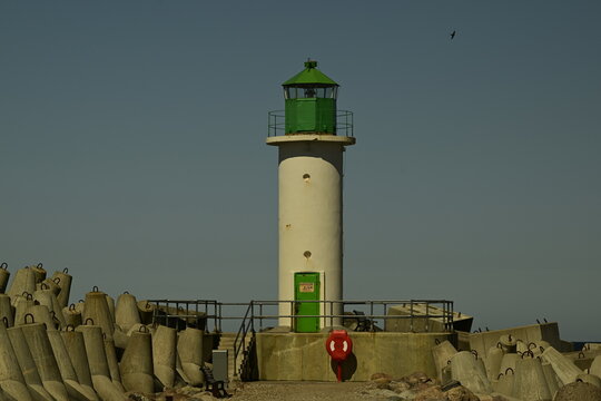 Green lighthouse on pier against clear blue sky