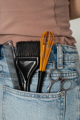 Professional hairdressing tools (scissors, brush, whisk) in a denim pocket. Barber and hair stylist...