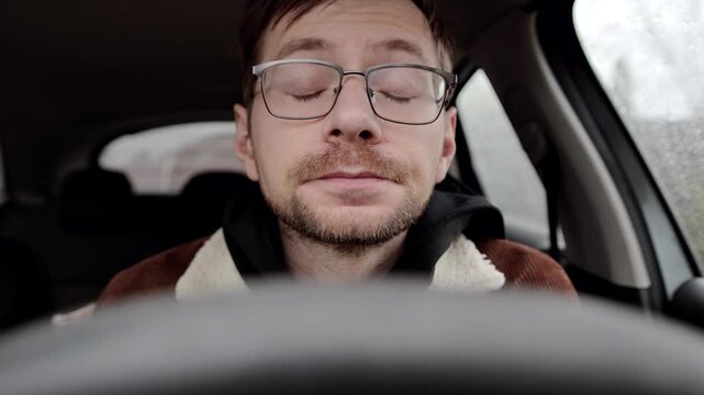 Young sick guy or allergic man sneezing inside a car.