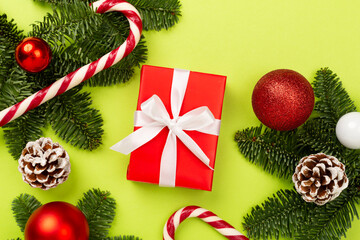 Festive Christmas tree branches with gift box on color background, top view