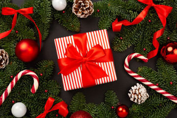 Festive Christmas tree branches with gift box on color background, top view