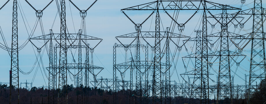 Dense network of electric transmission towers over farmland and forest.