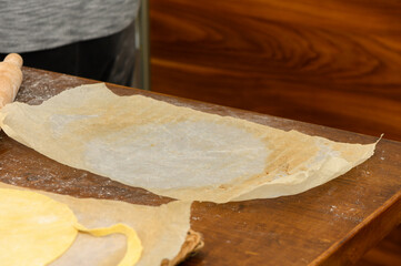 Woman rolling dough for Napoleon cake layers close-up
