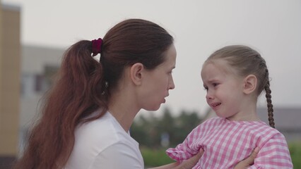 a small child sheds tears on the shoulder of an embracing mother, crying of an upset kid, childhood emotions of a capricious baby, a problem for an unhappy girl, experiencing pain of strong feelings.