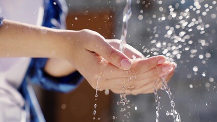 a man with white skin washes his hands with water close-up in the summer, skin hygiene and protection from coronavirus, wash his fingers, stop the spread of bacteria, splashes and drops fly bokeh.