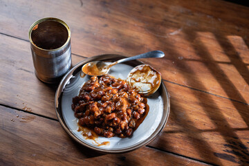 A can of chilly and a plate with chilly beans on it ready to be devoured