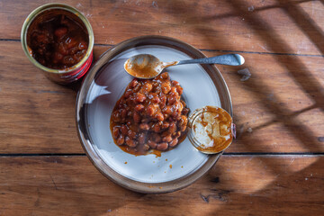 A can of chilly and a plate with chilly beans on it ready to be devoured