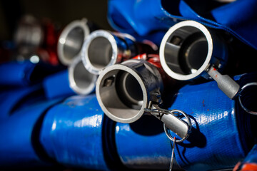 Close-up of blue industrial hoses with aluminum camlock couplings and locking pins showing flexible...